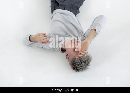 Young man lying on white floor Stock Photo