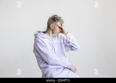 Stressed man sitting on chair against white background Stock Photo
