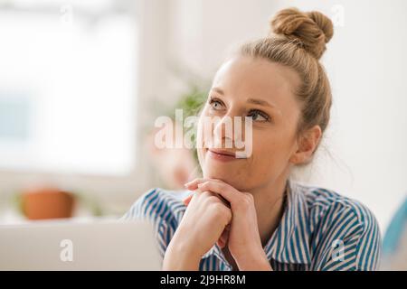 Contemplative freelancer with hand on chin at home Stock Photo