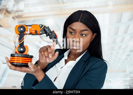 Engineer analyzing model of robotic arm in factory Stock Photo