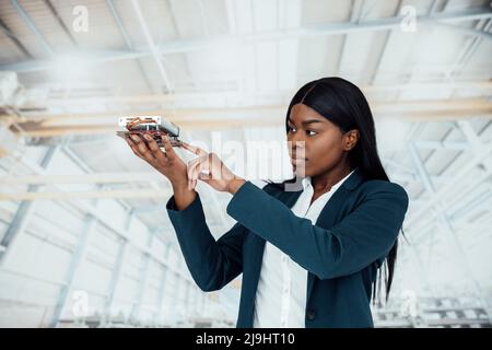 Businesswoman analyzing machine part standing in factory Stock Photo
