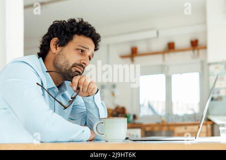 Sad businessman with eyeglasses looking at laptop in office Stock Photo