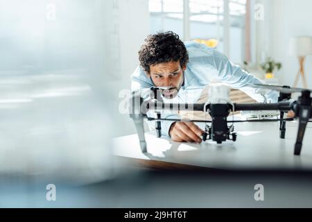 Businessman analyzing drone at desk in office Stock Photo