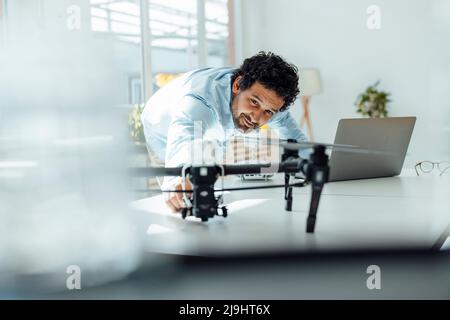 Smiling businessman analyzing drone at desk in office Stock Photo