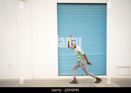 Playful young man dancing on footpath Stock Photo