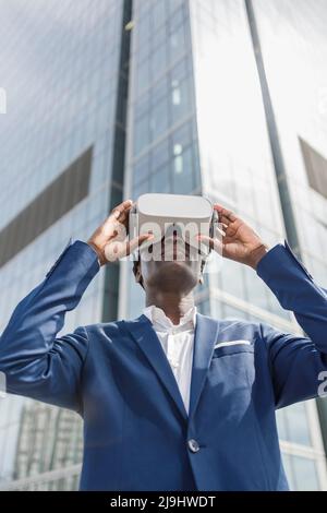Businessman wearing virtual reality simulator in front of modern building Stock Photo