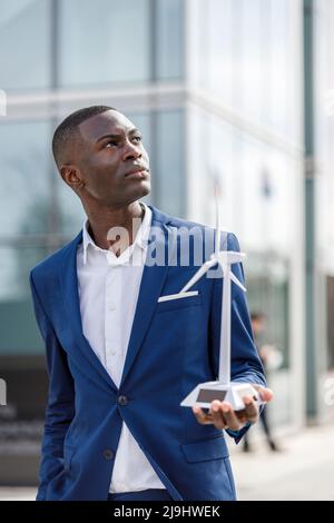 Thoughtful engineer holding wind turbine model Stock Photo