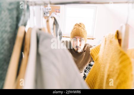 Young man searching for warm clothes in wardrobe Stock Photo