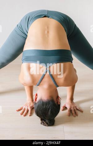 Woman practicing headstand at yoga studio Stock Photo
