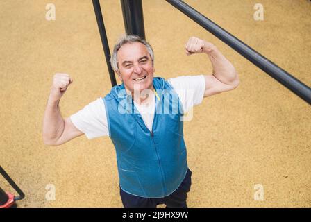 Confident senior man flexing muscles at park Stock Photo