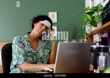 Overworked businesswoman suffering from headache using laptop at home Stock Photo