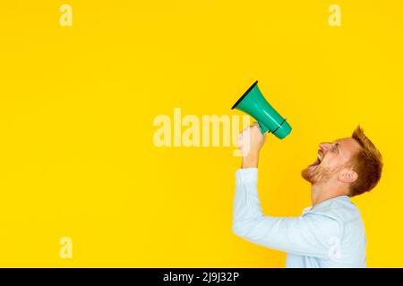Hipster trendy man screaming through megaphone over yellow background Stock Photo
