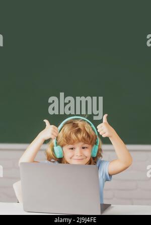 Cute boy wearing headphones, study with laptop in classroom, listening ...