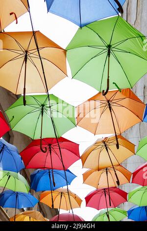 Umbrellas exhibition, street decorated. the sky is filled with colorful umbrellas. Many colorful umbrellas against the sky in city settings. Color bac Stock Photo