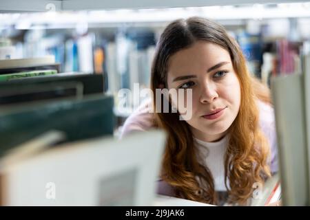 Portrait of woman choosing books at library Stock Photo
