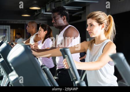 People having running elliptical trainer class in club Stock Photo