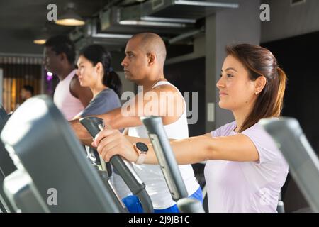 People having running elliptical trainer class in club Stock Photo