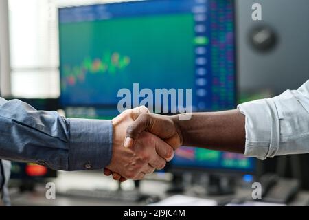 Unrecognizable ethnically diverse stock trading specialist and his client making great deal and doing handshake Stock Photo