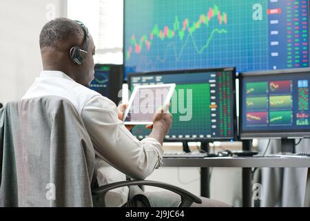 Young Black man holding digital tablet working with stock trading stats watching charts and graphs of currency Stock Photo