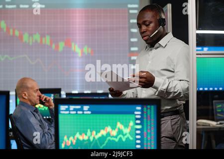 Modern professional business broker holding documents working in evening in modern office talking to clients on phone Stock Photo