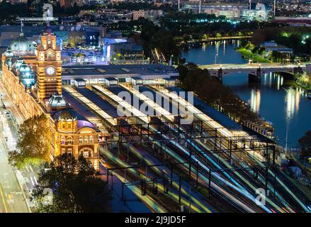 Melbourne, Australia - May 2, 2022: Flinders Street Railway Station in Melbourne CBD at night, multiple photos stacked to create train light trails Stock Photo
