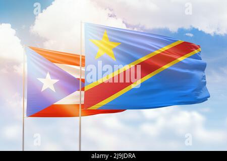 Sunny blue sky and flags of dr congo and puerto rico Stock Photo