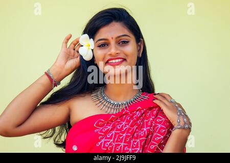 Closeup headshot portrait of attitude confident smiling happy pretty young woman background of blurred trees, plumeria flowers. Positive human emotion Stock Photo