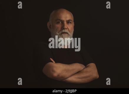 Senior man crossed arms on black. Portrait. Stock Photo