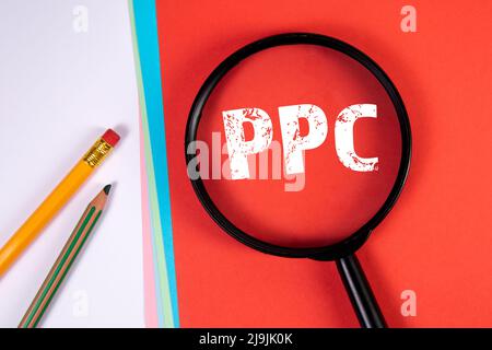 PPC pay per click advertising in the internet. Magnifying glass and office supplies. Stock Photo