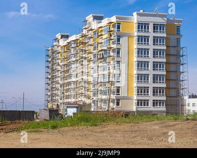 scaffolding installed around a multi-storey residential building - finishing work and landscaping of the surrounding area are being carried out, selec Stock Photo