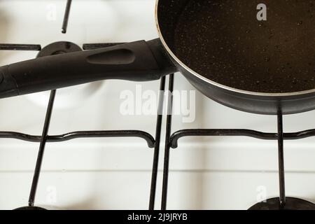 A frying pan stands on a gas stove at home in the kitchen, kitchen utensils and household appliances, cooking Stock Photo