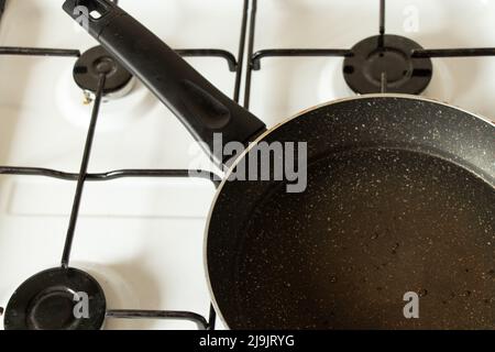 A frying pan stands on a gas stove at home in the kitchen, kitchen utensils and household appliances, cooking Stock Photo