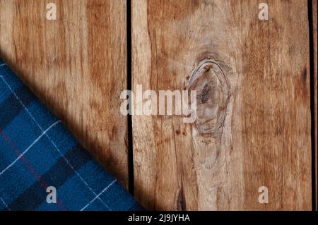 The blue checkered fabric lies against the wooden background. A towel or kitchen napkin on the rough boards or kitchen table. Stock Photo