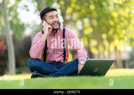 Man talking on a mobile while working on a laptop Stock Photo