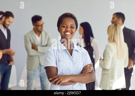 Portrait of happy black businesswoman and team leader standing in office and smiling Stock Photo