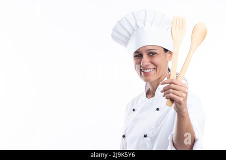 Portrait of happy caucasian woman looking at camera in chef outfit with kitchen tools in hands isolated on white background with copy space. Stock Photo