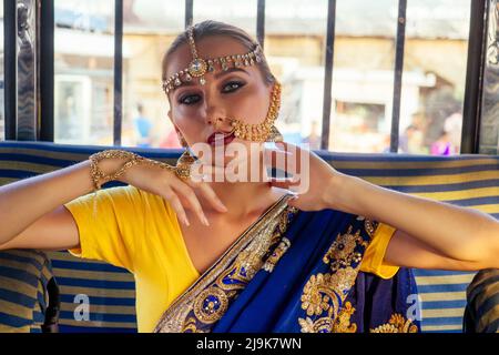 portrait indian beautiful Caucasian woman in traditional blue dress.hindu model with golden kundan jewelry set bindi earrings and nose ring piercing Stock Photo