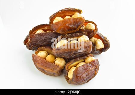 Organic fresh nutritious dried hurma dates medjool grains, hazelnuts placed inside the date, isolated on white background Stock Photo