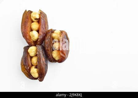 Organic fresh nutritious dried hurma dates medjool grains, hazelnuts placed inside the date, isolated on white background Stock Photo