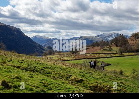 People tourists visitors walkers walking on footpath path on Gowbarrow Fell in spring Lake District National Park Cumbria England UK United Kingdom GB Stock Photo