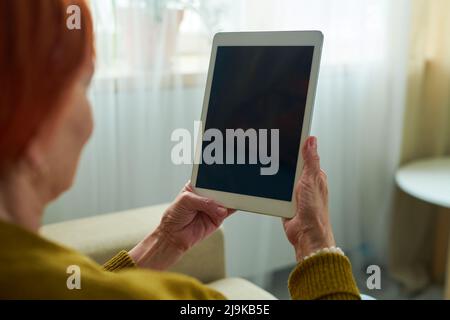 Close-up of elderly woman holding touchpad in front of her face and talking online with her grandchildren Stock Photo