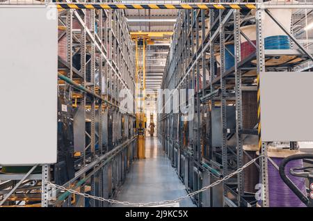 Interior of modern storage warehouse with coils of colored cable on metal shelves. Forklift lift at plant. Stock Photo