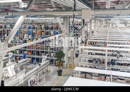 Interior of modern warehouse with coils of colored cable on metal shelves. Car wiring plant. Panoramic view. Stock Photo