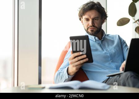 Portrait of focused man using digital tablet and pc Stock Photo
