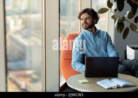 Businessman using laptop sitting on bean bag in office Stock Photo