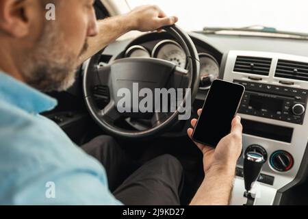 Driver man using smartphone with empty screen driving car Stock Photo