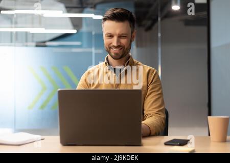 Confident Businessman Working Online On Laptop Computer In Modern Office Stock Photo
