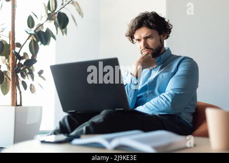 Focused business man using laptop sitting on beanbag chair Stock Photo