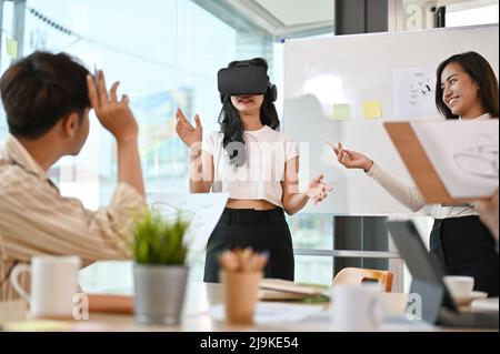 An Asian female graphic developer presenting her project in the meeting, a female user testing a VR game. Virtual reality innovation. Stock Photo