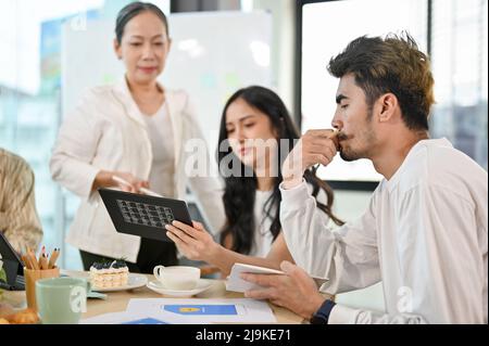A group of graphic designers and web developers are in the meeting with aged senior female executive manager. Stock Photo